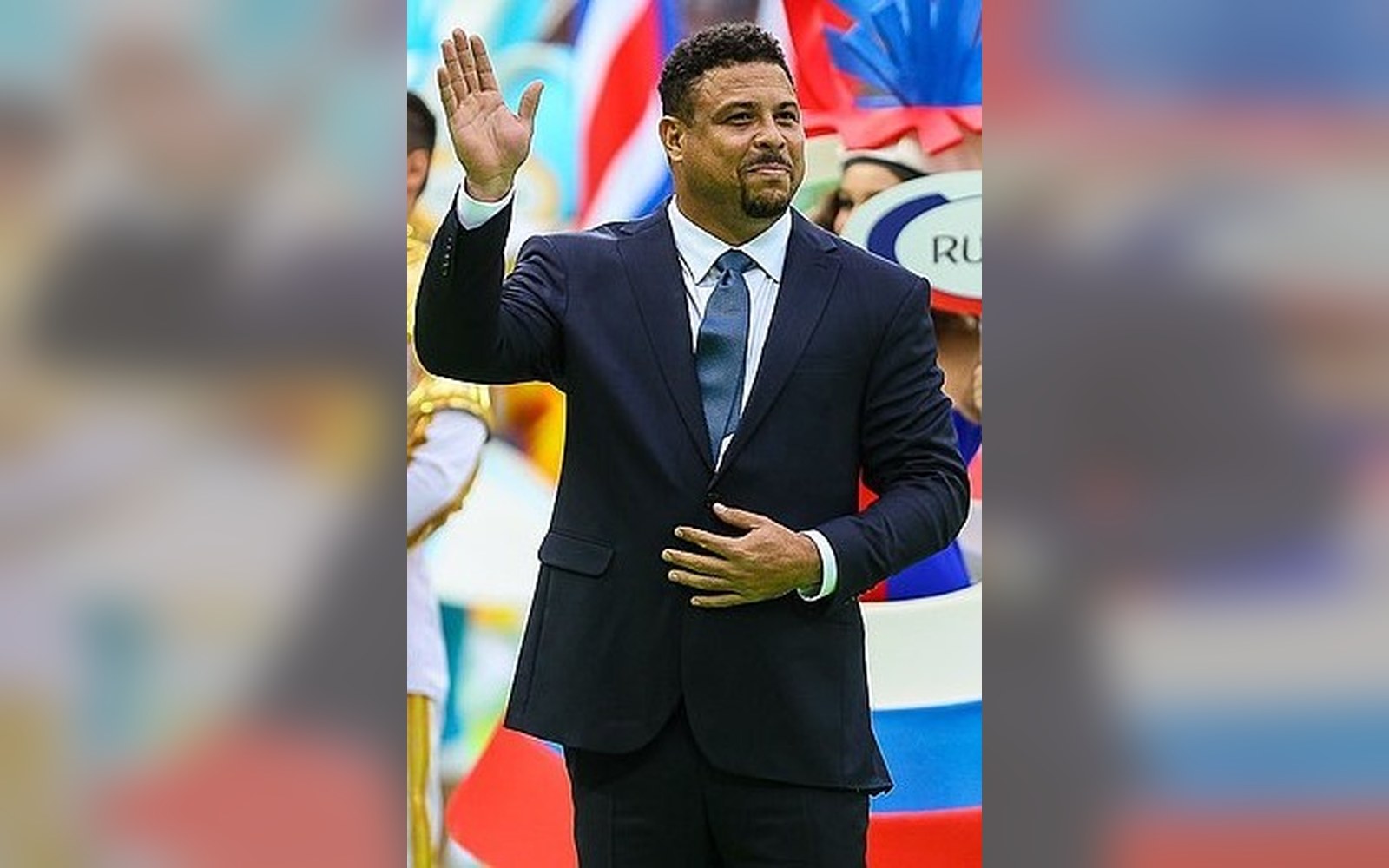 Ronaldo Nazário in a suit, acknowledging a crowd